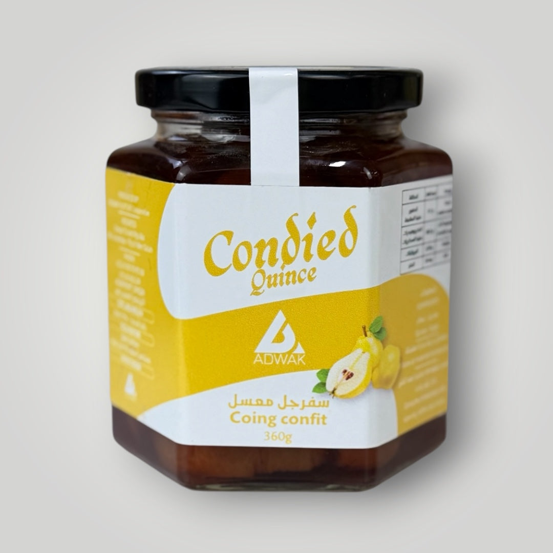 Bocal hexagonal en verre de 360 g de coing confit, couvercle métallique noir avec banderole blanche. Étiquette fond jaune vif avec inscription "Condied Quince – Coing confit 360g" en arabe et français, illustration d'un coing entier et coupé. Le contenu brun-ambré des coings confits dans leur sirop épais est visible à travers les parois du bocal. Fond gris clair dégradé.